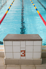 Starting blocks and lanes in a swimming pool. Edge of indoors sport swimming pool. Starting...