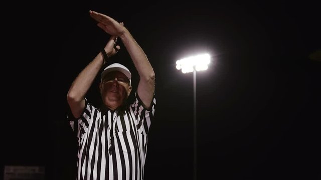 A football referee makes a personal foul hand gesture