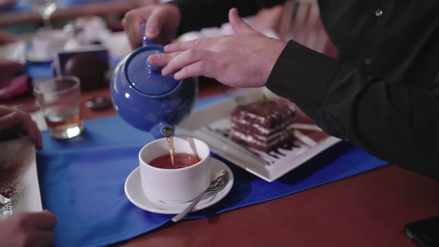 Man pouring black tea in a cup
