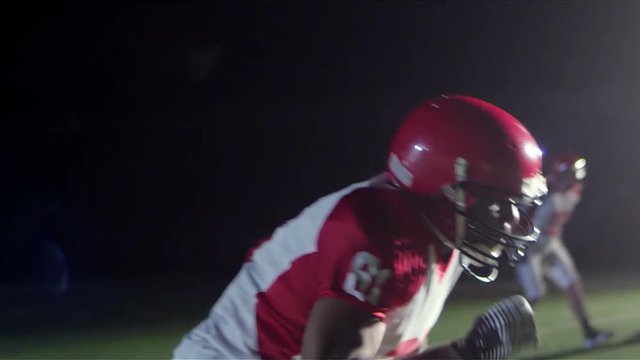 Close up tracking shot of a football player catching a pass while being defended