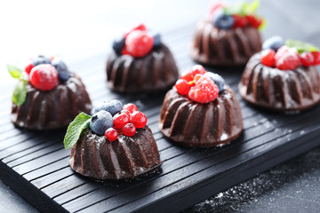 Sweet chocolate cakes with berries on black wooden table