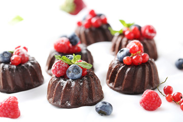 Sweet chocolate cakes with berries on white background