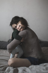 Fototapeta premium young mother and baby in knit sweaters playing on bed, concept