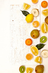 Colorful background with citrus fruits. Apple, mandarin, kiwi , lemon, pear on the white rustic wooden table. Copy space