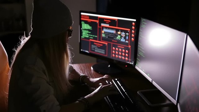 Hacker, programmer working with data code in a dark room. Hackers desk. HD.