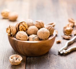 Walnuts in wooden bowl on table with Nutcracker.