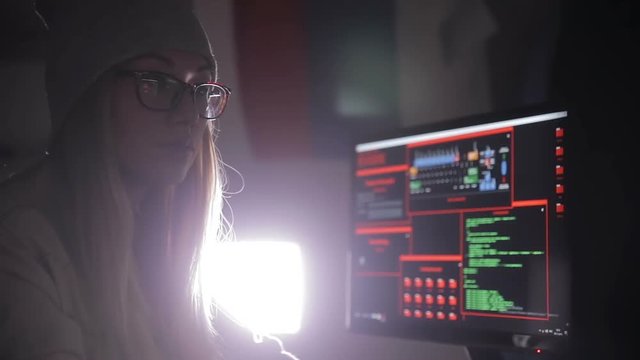 Female hacker working on a computer, coding at night. HD.