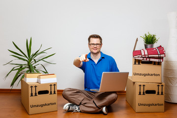 Junger Mann benutzt Laptop im neuen Eigenheim