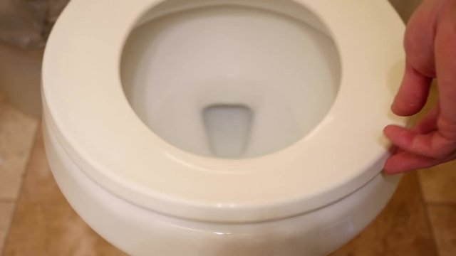 A man lifts the lid on the toilet in the bathroom