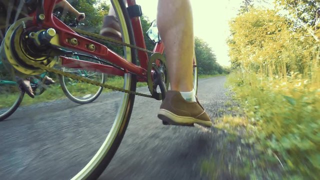 A fun shot of couple biking in a green forest on bike trail