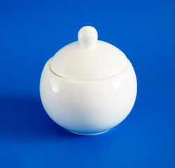 White sugar bowl with lid on blue background