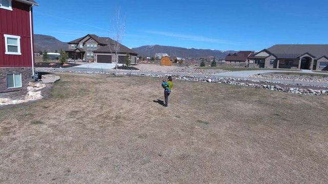 Aerial shot of mother with baby walking across the grass