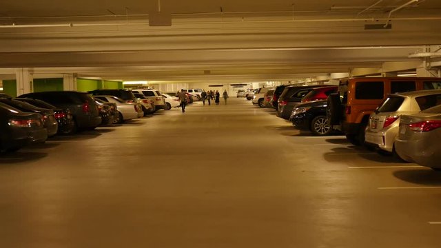 People in full underground parking garage with lots of cars