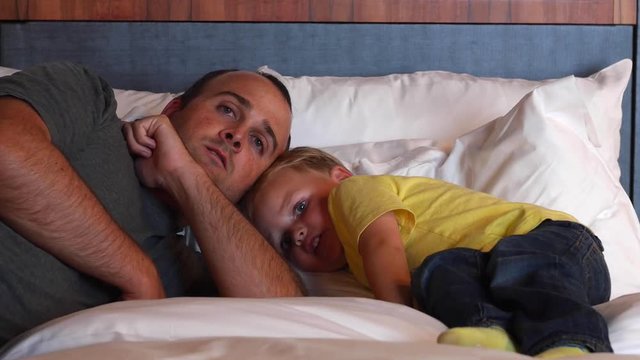 A father and boy in bed at a modern hotel room