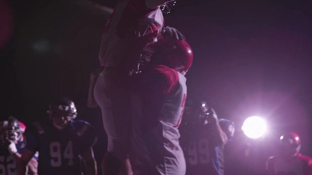 A football player celebrates and jumps into his teammates arms after a touchdown