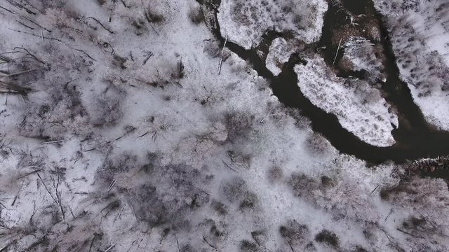 A high aerial shot of river and snowy trees rotating into clouds