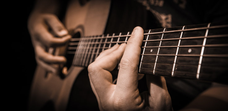 Close up hands on the strings of a guitar