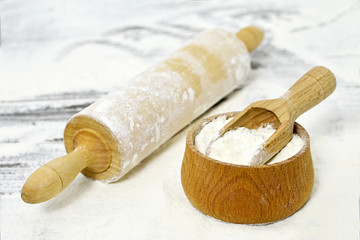 Wheat flour in wooden bowl and rolling-pin