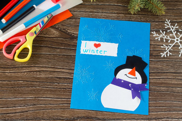 The child makes a greeting card with a snowman. Glue, paper, sci