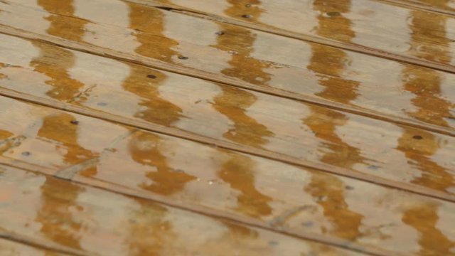Raindrops fall on to wooden deck