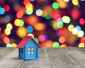 Little house in a gift on blurred background with bokeh.
