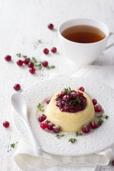 Cheesecake, cottage cheese pudding with cranberry jam, fresh cranberries and thyme on a white plate on a old white background, selective focus 