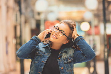 Smiling beautiful woman using cellphone outdoors.

