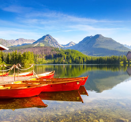 Dreamy red boats stand at the pier on a quiet lake.