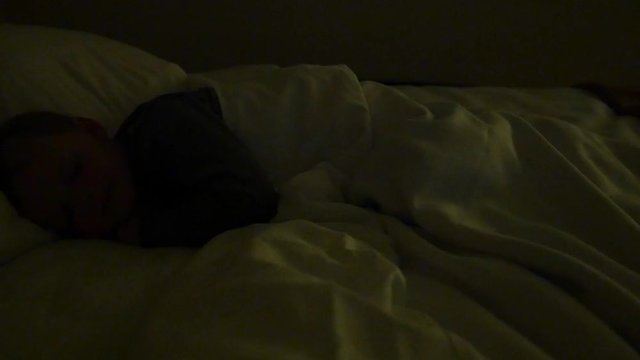 Little boy sleeping in a hotel bed at night dolly shot