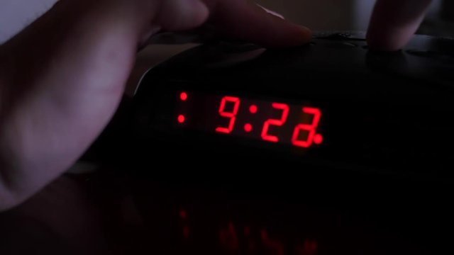 A man sets digital alarm clock time