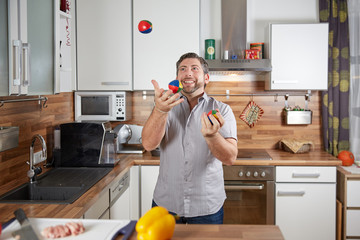 Man juggling in the kitchen with tomatoes