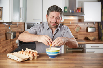 Man cracking egg in the kitchen for cooking