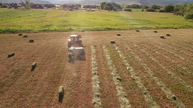 Aerial beautiful high shot as farmer cuts and bails his hay
