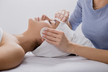 Young woman enjoying facial massage at spa salon