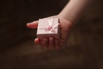 Hand of child holding a small pink gift box