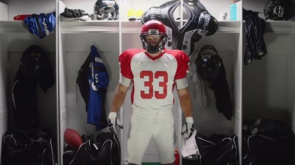 A football player stands in his locker and gets hyped up to play