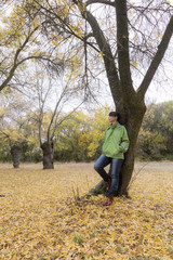 Woman sitting on a park bench with yellow leaves falling from trees