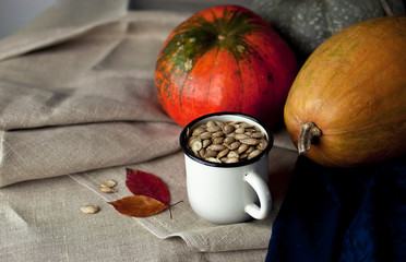 Autumn composition: persimmon, pumpkin, pumpkin seeds with autumn leaves