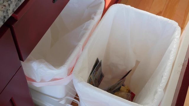A man throws a can into the trash in kitchen