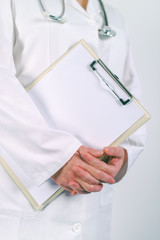 Female doctor in white uniform posing with blank clipboard pad