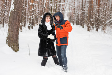 Fototapeta na wymiar Young couple playing in snow, having snowball fight