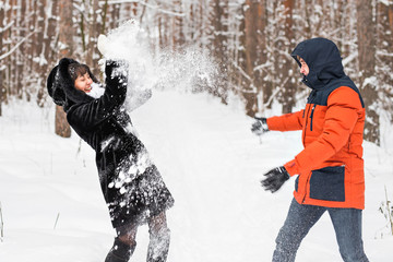 Young couple playing in snow, having snowball fight