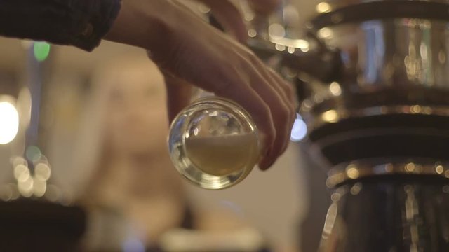 woman pours beer into a glass