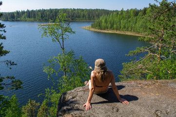 woman enjoys views of the lake. A relax on the lakeshore with forest arround. Supervision over the horizon.