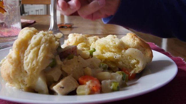 Man eating chicken pot pie made with biscuits