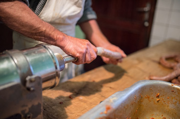 Man making sausages the traditional way using sausage filler.