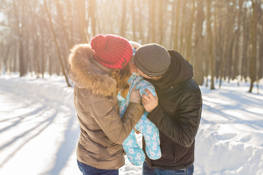 Mother And Father Holding Their Baby Boy And Kissing His Outside In The Winter