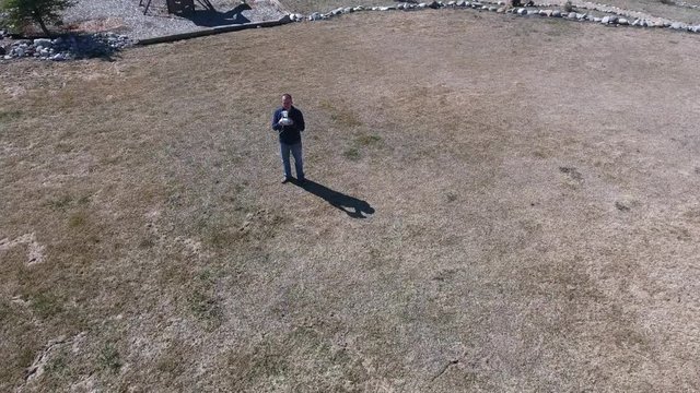 An aerial shot of a man using remote to fly drone