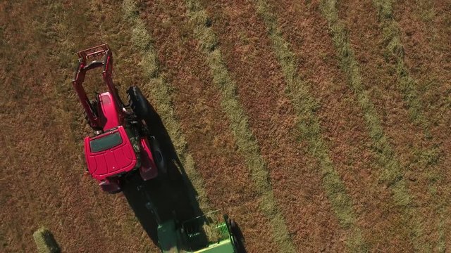 Aerial clip as a farmer cuts and bails hay with a tractor