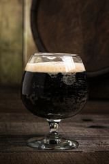 Russian Imperial Stout in snifter glass on wood background and b